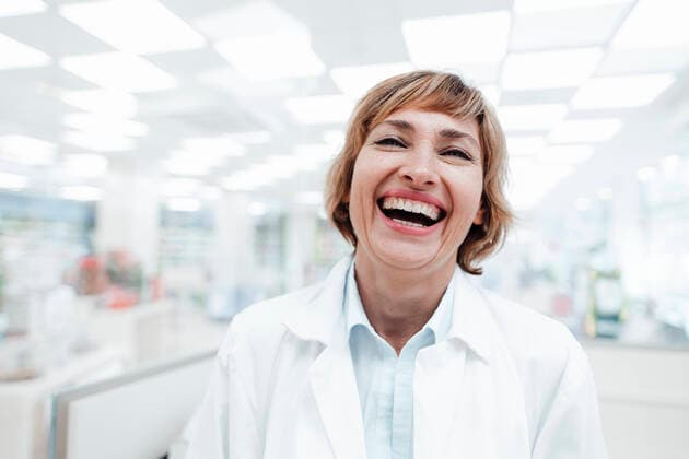 Happy female pharmacist laughing in medical store model released Symbolfoto property released JOSEF05477