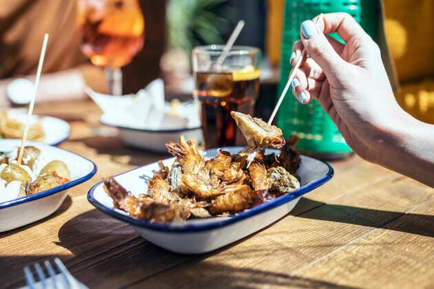 IMAGO Creative, Food, Tapas Woman having fried prawn in restaurant model released Symbolfoto property released JSRF01578