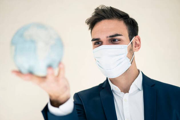 Young businessman looking at globe while working in office during COVID-19 model released Symbolfoto property released MOEF03903