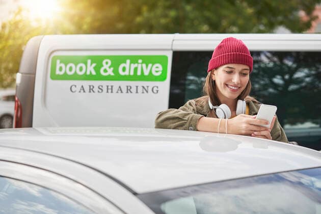 Smiling young woman using mobile phone while leaning on car model released Symbolfoto property released RORF02838