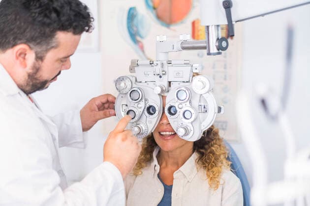 Male optometrist adjusting phoropter while checking female patient s eyesight model released Symbolfoto SIPF02345