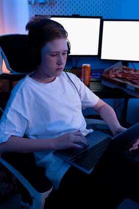 IMAGO Creative: Sport Start-Up Gamer boy using laptop while sitting on chair at home model released Symbolfoto property released VPIF04632