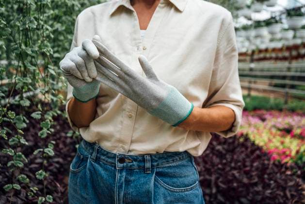 IMAGO Creative, Frühling, Start der Garten-Saison Creative Highlights Symbolbilder IMAGO Creative: Klimawandel - Zukunft und Innovation Female agriculture worker removing protective glove while standing in plant nursery model released Symbolfoto property released VPIF04702