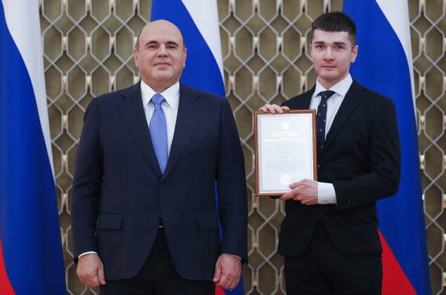 MOSCOW, RUSSIA - OCTOBER 5, 2021: Russia s Prime Minister Mikhail Mishustin (L) poses with Artyom Malykh, lab assistant at the Psychological Institute of the Russian Academy of Education, during a ceremony to award commendations and state prizes in the field of education and mark Teachers Day. Dmitry Astakhov POOL TASS  TS113220