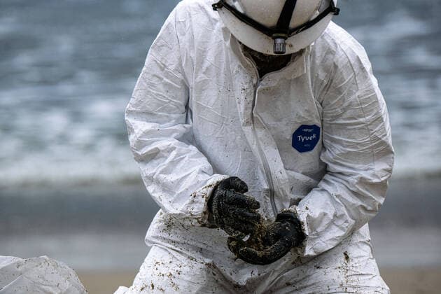 October 4, 2021, Huntington Beach, California, USA: A worker in a protective suit cleans up an area of the beach after a major oil spill dumped 126,000-gallon oil from an offshore oil platform. A massive oil spill off the Orange County coast in Southern California prompted the closure of a 9-kilometer long beachfront area and crews from the California Department of Fish and Wildlife (CDFW) are cleaning up the pollution from facilities in federal waters. Huntington Beach USA  - ZUMAr145 20211004_new_r145_034 Copyright: xJasonxRyanx