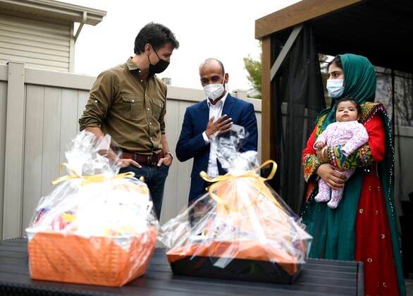 October 9, 2021, Ottawa, on, Canada: Prime Minister Justin Trudeau speaks with Obaidullah Rahimi, right, his wife Arezoo, and daughter Hawa, 2 months, after assembling care packages for the recently resettled Afghan family for Thanksgiving in Ottawa, on Saturday, Oct. 9, 2021. Obaidullah Rahimi worked at the Canadian Embassy in Afghanistan; his family is one of 22 resettled Afghan families in the Ottawa area. Ottawa Canada - ZUMAc35_ 20211009_zaf_c35_010 Copyright: xJustinxTangx