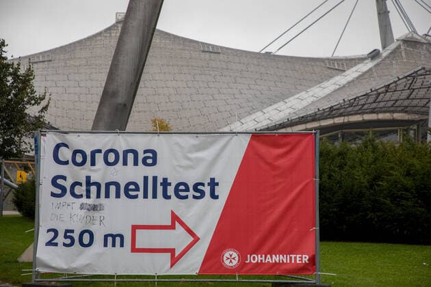 Muenchen, Deutschland 08. Oktober 2021: Vor dem Olympiastadion in München steht ein Werbebanner, Wegweiser für ein Corna-Schnelltest der Johanniter. Auf den Banner wurde handschriftlich ein Zusatz, impft die Kinder, geschrieben Bayern Copyright: xFotostandx xFritschx
