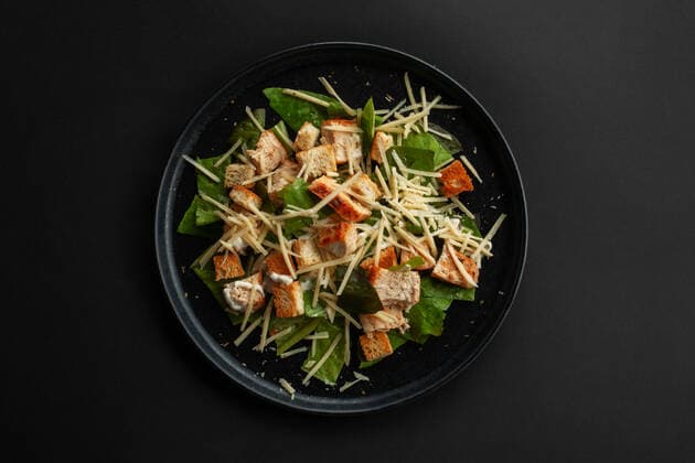 Caesar salad top view Caesar salad top view on black table over black table background Copyright: xMikhailovaxLiubovx 36570292