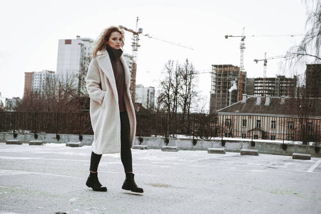 IMAGO Creative: Jahreszeit Winter, Spaziergang A girl with red curly hair in white coat. City construction in the background A girl with red curly hair in a white coat poses on outdoor parking in cold autumn. City Style - Urban. City construction in the background Copyright: xx 37914638