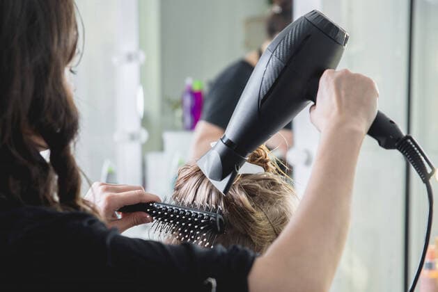 Close up of hairdressers hands drying long blond hair with blow dryer and round brush Close up of hairdressers hands drying long blond hair with blow dryer Copyright: xAleksey_Semykinx+7(996)4187859x 38914972