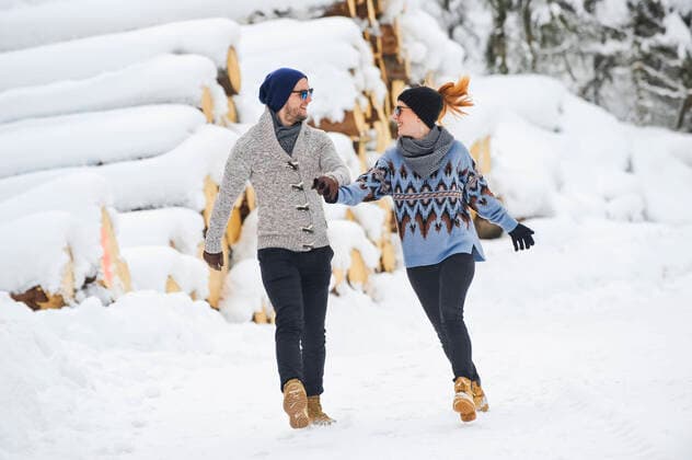 IMAGO Creative: Countdown bis Weihnachten, Nach Hause reisen Mid adult couple in warm clothing holding hands while walking on snow model released Symbolfoto HHF05710