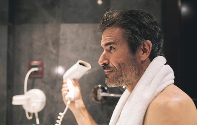 Man drying hair in hotel room model released Symbolfoto property released JCCMF04039