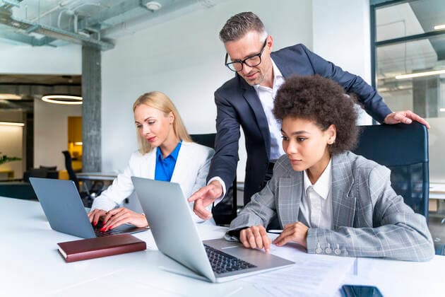Male business professional explaining female colleague over laptop at desk model released Symbolfoto property released OIPF01191