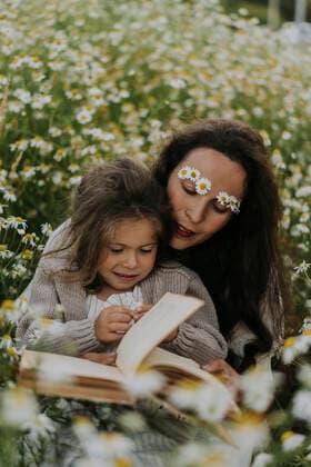 Mother reading book with daughter at flower field model released Symbolfoto SSGF00038