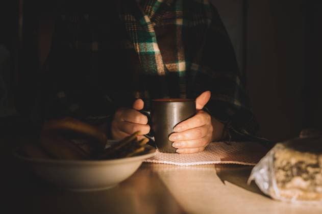 Woman in plaid shawl warms her hands with hot cup at table Belgorod, Belgorod Oblast, Russia CR_GWEHXZ21101816-849113-01 ,model released, Symbolfoto