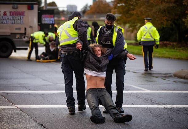 October 25, 2021, Richmond, BC, Canada: RCMP officers drag a man away as they take him into custody after the environmental activist group Extinction Rebellion blocked the main road used to access Vancouver International Airport, in Richmond, B.C., Monday, Oct. 25, 2021. More than a dozen people were arrested and traffic to and from the airport was diverted due to the protest which was part of the group s two week October Rebellion action. Richmond Canada  - ZUMAc35_ 20211025_zaf_c35_132 Copyright: xDarrylxDyckx