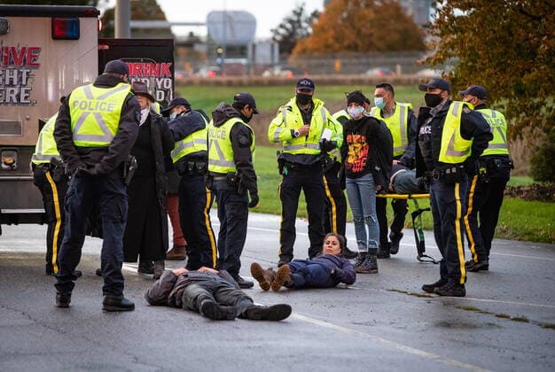 October 25, 2021, Richmond, BC, Canada: RCMP officers process protesters that were taken into custody after the environmental activist group Extinction Rebellion blocked the main road used to access Vancouver International Airport, in Richmond, B.C., Monday, Oct. 25, 2021. More than a dozen people were arrested and traffic to and from the airport was diverted due to the protest which was part of the group s two week October Rebellion action. Richmond Canada  - ZUMAc35_ 20211025_zaf_c35_134 Copyright: xDarrylxDyckx