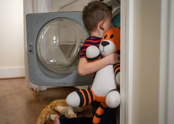 IMAGO Creative: Jahreszeit Winter, Fantasievoll drinnen spielen Young boy putting stuffed tiger into the washing machine Arlington, Virginia, United States CR_SUSU21091477-829305-01 ,model released, Symbolfoto