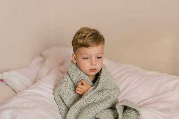 Ill and tired boy wrapped in grey blanket sitting on bed Gryfino, West Pomeranian Voivodeship, Poland CR_XCKH211021C-853446-01 ,model released, Symbolfoto