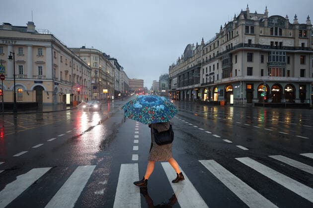 MOSCOW, RUSSIA - OCTOBER 28, 2021: A woman with an umbrella crosses a road in the city s centre. A recent surge in COVID-19 cases in Russia has prompted the Moscow authorities to declare non-working days with pay from October 28 to November 7. Sergei Bobylev TASS  TS1160A8