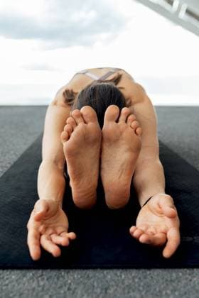 Unrecognizable flexible barefoot female practicing Paschimottanasana posture on mar during yoga training near solar panel on street in Barcelona city, Model released SergioVictorVega_GalaForum_74.jpg Copyright: xSergioxVictorxVegax MR