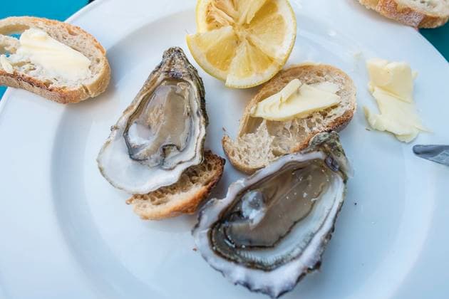 Auf einem Tisch steht ein Teller mit frischen Austern (Ostreidae), Zitrone und Brot, daneben ein Baguette und Weingläser mit Weisswein. Arcachon, Bordeaux (Gironde), Nouvelle Aquitaine, Frankreich. Austern an der französischen Atlantikküste *** On a table there is a plate with fresh oysters Ostreidae , lemon and bread, next to it a baguette and wine glasses with white wine Arcachon, Bordeaux Gironde , Nouvelle Aquitaine, France Oysters on the French Atlantic Coast