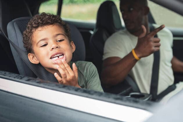 Playful boy showing broken teeth while sitting by father in electric car Sweden, Skane, model released, property released Copyright: xMaskotx , MA89537