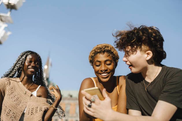 IMAGO Creative: Pride Month 2022, Engagement der Jugendlichen Teenage boy sharing smart phone to young friends on sunny day Sweden, Malmo, model released Copyright: xMaskotx , MA89727