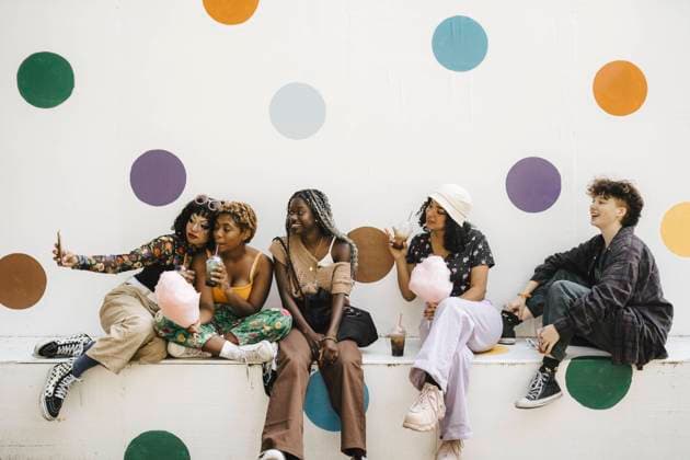 Smiling LGBTQIA friends taking selfie through smart phone against polka dots wall Sweden, Malmo, model released Copyright: xMaskotx , MA89766