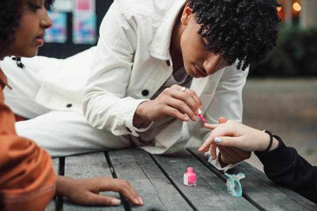 Teenage boy applying pink nail polish to female friend at table Sweden, Stockholm, model released Copyright: xMaskotx , MA89959