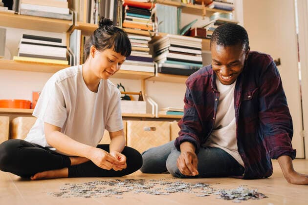 Smiling couple playing jigsaw puzzle on floor at home Sweden, Stockholm, model released, property released Copyright: xMaskotx , MA90014