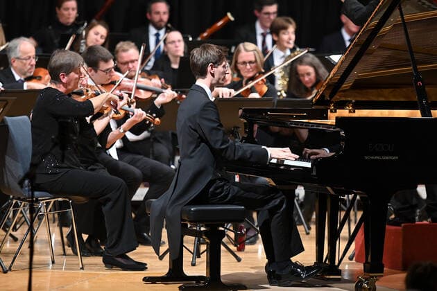 Konzert des Orchesters der Gesellschaft der Musikfreunde Gmunden, im Toskana Kongress, im Rahmen der Salzkammergut Festwochen in Gmunden, am 30.10.21. Das Bild zeigt den Pianisten Florian Feilmair im Spiel, mit ihn umgebenden Geigern 2021 - Konzert des Orchesters der Gesellschaft der Musikfreunde Gmunden, im Toskana Kongress, im Rahmen der Salzkammergut Festwochen in Gmunden, am 30.10.21