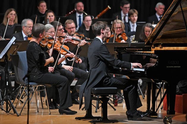 Konzert des Orchesters der Gesellschaft der Musikfreunde Gmunden, im Toskana Kongress, im Rahmen der Salzkammergut Festwochen in Gmunden, am 30.10.21. Das Bild zeigt den Pianisten Florian Feilmair im Spiel, mit ihn umgebenden Geigern 2021 - Konzert des Orchesters der Gesellschaft der Musikfreunde Gmunden, im Toskana Kongress, im Rahmen der Salzkammergut Festwochen in Gmunden, am 30.10.21