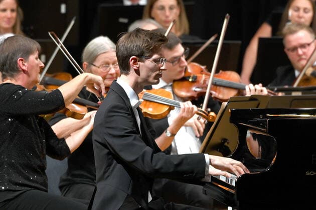 Konzert des Orchesters der Gesellschaft der Musikfreunde Gmunden, im Toskana Kongress, im Rahmen der Salzkammergut Festwochen in Gmunden, am 30.10.21. Das Bild zeigt den Pianisten Florian Feilmair im Spiel, mit ihn umgebenden Geigern 2021 - Konzert des Orchesters der Gesellschaft der Musikfreunde Gmunden, im Toskana Kongress, im Rahmen der Salzkammergut Festwochen in Gmunden, am 30.10.21