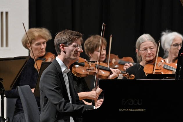Konzert des Orchesters der Gesellschaft der Musikfreunde Gmunden, im Toskana Kongress, im Rahmen der Salzkammergut Festwochen in Gmunden, am 30.10.21. Das Bild zeigt den Pianisten Florian Feilmair im Spiel, mit ihn umgebenden Geigerinnen 2021 - Konzert des Orchesters der Gesellschaft der Musikfreunde Gmunden, im Toskana Kongress, im Rahmen der Salzkammergut Festwochen in Gmunden, am 30.10.21