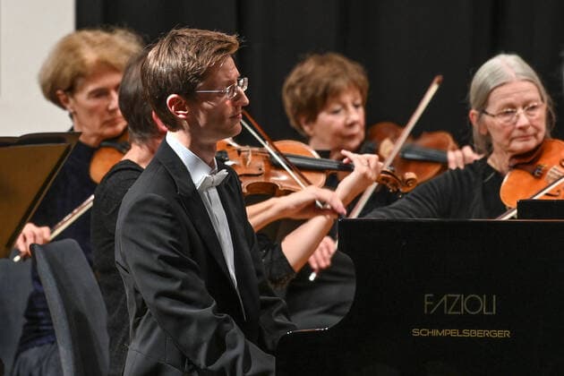 Konzert des Orchesters der Gesellschaft der Musikfreunde Gmunden, im Toskana Kongress, im Rahmen der Salzkammergut Festwochen in Gmunden, am 30.10.21. Das Bild zeigt den Pianisten Florian Feilmair im Spiel, mit ihn umgebenden Geigerinnen 2021 - Konzert des Orchesters der Gesellschaft der Musikfreunde Gmunden, im Toskana Kongress, im Rahmen der Salzkammergut Festwochen in Gmunden, am 30.10.21
