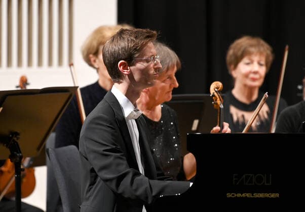 Konzert des Orchesters der Gesellschaft der Musikfreunde Gmunden, im Toskana Kongress, im Rahmen der Salzkammergut Festwochen in Gmunden, am 30.10.21. Das Bild zeigt den Pianisten Florian Feilmair im Spiel, mit ihn umgebenden MusikerInnen 2021 - Konzert des Orchesters der Gesellschaft der Musikfreunde Gmunden, im Toskana Kongress, im Rahmen der Salzkammergut Festwochen in Gmunden, am 30.10.21