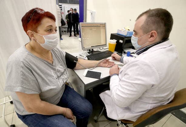 ST PETERSBURG, RUSSIA - NOVEMBER 8, 2021: A woman talks to a doctor before vaccination at a COVID-19 vaccination site at the Zanevsky Kaskad shopping mall. Alexander Demianchuk TASS  TS11714C