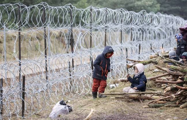 GRODNO REGION, BELARUS â€“ NOVEMBER 12, 2021: Migrant children near a barbed wire fence in a tent camp on the Belarusian-Polish border. Since the start of 2021, migrants have been heading to the border of Belarus with Poland, Lithuania and Latvia which escalated into a migrant crisis on 8 November 2021. Several thousand migrants have approached the Belarusian-Polish border and set up a tent camp there. Some of them have attempted to cross the border into Poland by breaking a barbed wire fence. Leonid Shcheglov BELTA TASS EDITORIAL USE ONLY; NO COMMERCIAL USE; NO ADVERTISING  TS117AAF