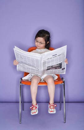 IMAGO Creative: 2022 Farbe des Jahres: Very Peri, Veilchenblau Creative Highlights Symbolbilder IMAGO Creative: NGO, Ausbildung für Kinder Portrait of little girl sitting on chair with newspaper model released, FS00901