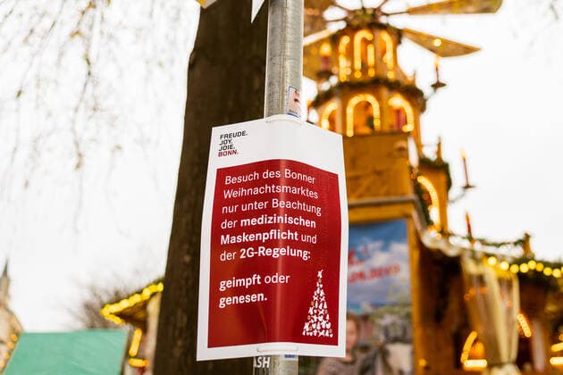 Hinweisschild der Stadt Bonn mit der Aufschrift: Besuch des Weihnachtsmarktes nur unter Beachtung der medizinischen Maskenpflicht und der 2G-Regelung: geimpft oder genesen - Eröffnungstag des Weihnachtsmarktes 2021 auf dem Münsterplatz in Bonn. 17.10.2021 Bonn Innenstadt NRW Deutschland