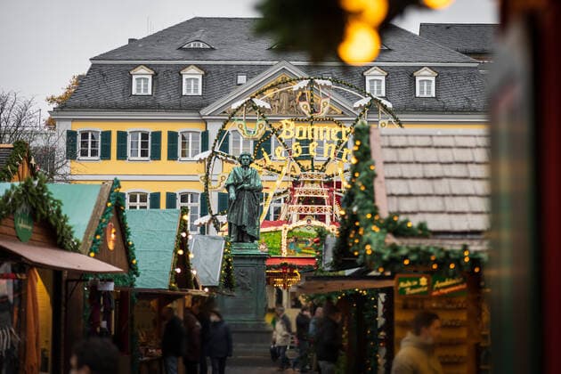 Das Beethoven Denkmal vor dem Bonner Riesenrad inmitten des Weihnachtsmarktes - Eröffnungstag des Weihnachtsmarktes 2021 auf dem Münsterplatz in Bonn. Aufgrund den stark angestiegenen Infektionen am Corona Virus darf der Markt nur von Menschen besucht werden, die die 2G Regel (geimpft oder genesen) erfüllen. 17.10.2021 Bonn Innenstadt NRW Deutschland