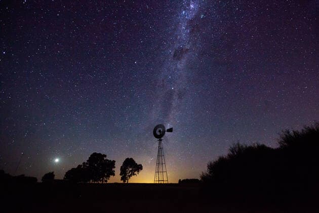 IMAGO Creative: Landleben, Mit Nachhaltigkeit grün auf dem Land leben View of aermotor windmill against milky way in sky Copyright: PabloxCamacho B33816643