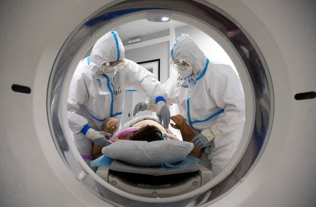 News Bilder des Tages Russia Coronavirus Treatment 6699986 19.11.2021 Medical specialists wearing protective gear prepare a patient for a CT scan at a pavilion of the Exhibition of Achievements of National Economy (VDNH), which was converted into a reserve hospital for people suffering from the coronavirus disease, in Moscow, Russia. Ilya Pitalev Sputnik Moscow Russia  Copyright: xIlyaxPitalevx