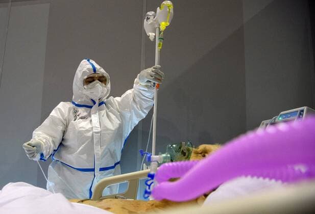 Russia Coronavirus Treatment 6700025 19.11.2021 A medical specialist wearing protective gear treats a patient at an intensive care ward at a pavilion of the Exhibition of Achievements of National Economy (VDNH), which was converted into a reserve hospital for people suffering from the coronavirus disease, in Moscow, Russia. Ilya Pitalev Sputnik Moscow Russia  Copyright: xIlyaxPitalevx