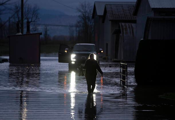 November 19, 2021, ABBOTSFORD, BC, CANADA: Sara Dejong is silhouetted by the headlights of a truck as she walks through flood waters after bringing her husband some food in Barrowtown near Abbotsford, B.C., Friday, November 19, 2021. ABBOTSFORD CANADA  - ZUMAc35_ 20211119_zaf_c35_156 Copyright: xJonathanxHaywardx