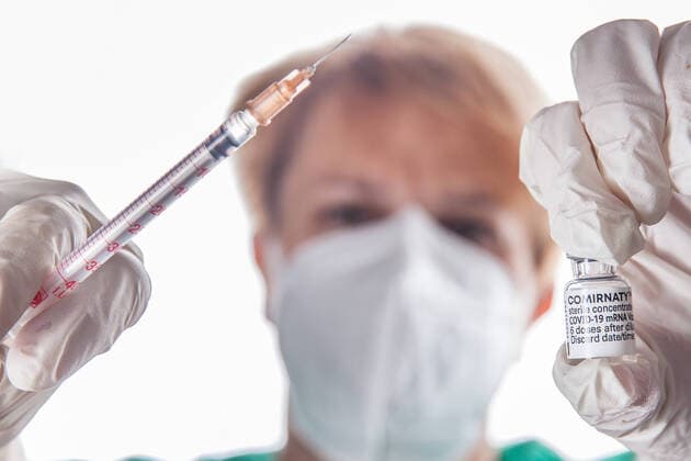 Bamberg, Deutschland 22. November 2021: Eine Person mit Schutzhandschuhen hat mit Hilfe einer Impfspritze eine Impfdosis mit dem mRNA-Impfstoff Comirnaty, BNT162b2, Biontech Pfizer aus einer Ampulle für die Erstimpfung- Zweitimpfung oder Boosterimpfung aufgezogen gegen das Coronavirus Covid 19. Bayern Copyright: xFotostandx xK.xSchmittx