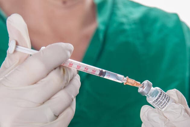 Bamberg, Deutschland 22. November 2021: Eine Person mit Schutzhandschuhen hat mit Hilfe einer Impfspritze eine Impfdosis mit dem mRNA-Impfstoff Comirnaty, BNT162b2, Biontech Pfizer aus einer Ampulle für die Erstimpfung- Zweitimpfung oder Boosterimpfung aufgezogen gegen das Coronavirus Covid 19. Bayern Copyright: xFotostandx xK.xSchmittx