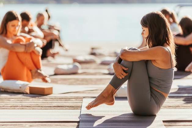 Female instructor hugging knees during yoga class model released property released, DAWF02039