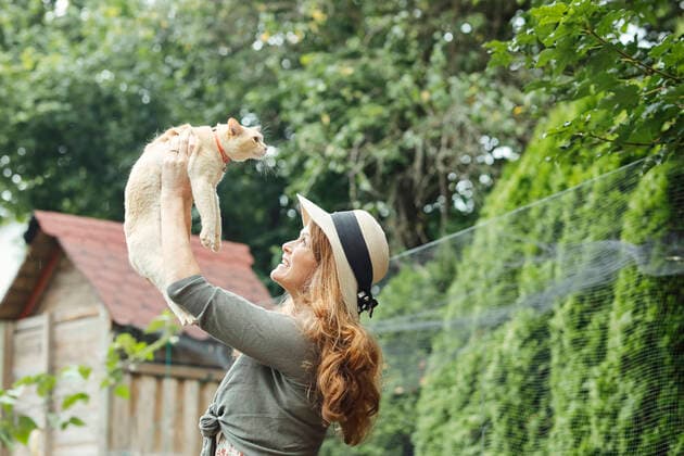 IMAGO Creative: Internationaler Frauenmonat, Gesundheit, Frauen in der Menopause Smiling mature woman lifting cat in backyard model released property released, Stockdorf Bayern Deutschland Bennostrasse 8 AANF00153